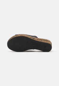 Semelle en caoutchouc noire avec surface texturée, dotée d'une semelle intermédiaire en bois et en liège superposés, aux lignes épurées et au design minimaliste.