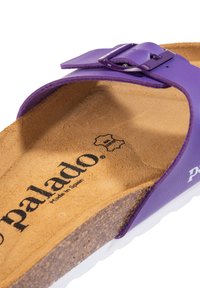 Lila flip-flop sandal med övre del i läder, korkinsats och vit gummisula. Har ett metallspänne och präglad varumärkeslogotyp.