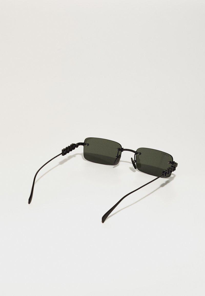Lunettes de soleil rectangulaires avec des verres vert foncé, une monture et des branches noires, présentant des accents texturés sur les tempes pour un maintien sécurisé.