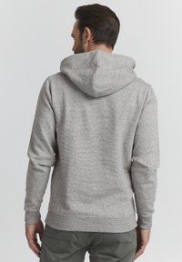 Grauer Kapuzenpullover mit strukturiertem Strickfinish, von hinten gezeigt, mit einer auffälligen Kapuze, gerippten Bündchen und einem taillierten Saum.