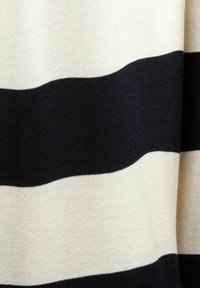 Tissu avec de larges rayures horizontales noires et blanches, texture tricotée avec de légers plis visibles.