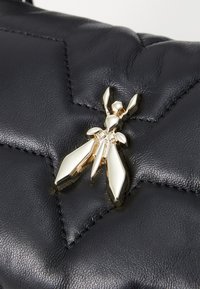 Black quilted leather handbag featuring a gold insect-shaped decorative hardware detail at the front, highlighting an intricate design.