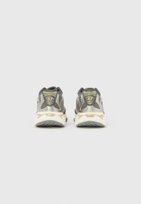 Hallide ja beežide sportlike jalanõude paar tagantvaates, valgel taustal võrgust ja sünteetilistest detailidest.