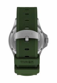 Zielony silikonowy pasek do zegarka z srebrną klamrą z wygrawerowanym napisem "TIMEX" oraz teksturowanym srebrnym tyłem koperty zegarka widocznym za paskiem.