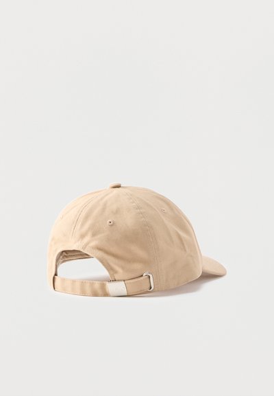 Casquette de baseball en coton beige vue de dos avec une sangle réglable en métal sur un fond clair uni.