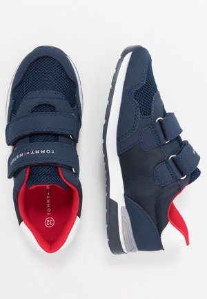 Marineblå børnesneakers med rød indvendig foring, hvide såledekorationer, meshstof og to velcrolukninger på hvid baggrund.