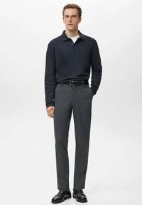 Temno modra polo majica z dolgimi rokavi in ovratnikom, kombinirana s sivimi, po meri krojenimi hlačami in črnimi usnjenimi čevlji. Preprost dizajn, gladka tekstura, prilegajoč se kroj.