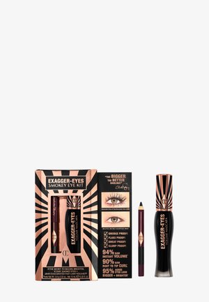 Das Exagger-Eyes Smokey Eye Kit umfasst eine schwarze Mascara in einer glänzenden Flasche und einen lila Eyeliner-Stift, präsentiert in einer gemusterten Box mit Text.