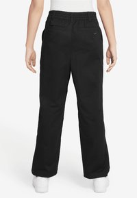 Pantalon cargo noir avec une taille élastique, doté de deux poches arrière et d'un petit logo sur la hanche droite. Fabriqué en tissu durable.