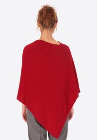 Poncho rosso con una vestibilità ampia, realizzato in tessuto morbido, con un ampio scollo e una forma triangolare che si drappeggia sulle spalle.
