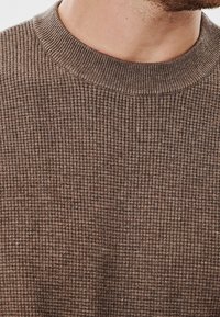 Brązowy sweter z prążkowanej dzianiny z okrągłym dekoltem, prezentujący fakturowany materiał i jednolity wzór w całej długości.