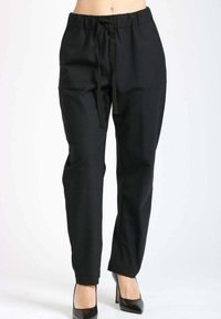 Pantaloni neri a vita alta, a sigaretta, con vita regolabile, indossati con scarpe col tacco a punta nere, mostrati su una persona dalla vita ai piedi.