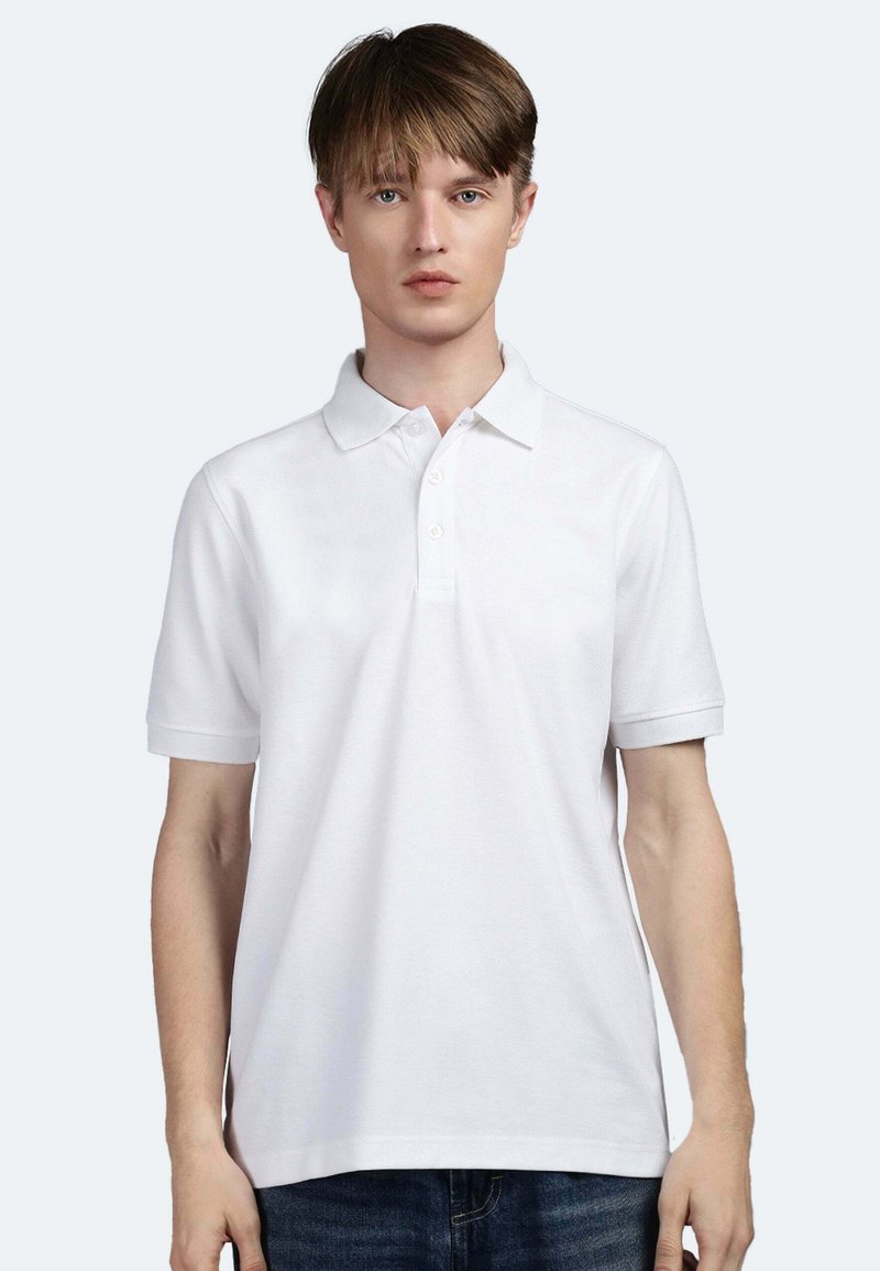 Polo shirt bianco con maniche corte, colletto abbottonato e tessuto texturizzato, indossato da un modello su uno sfondo chiaro.