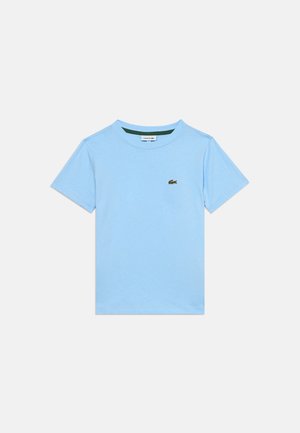 T-shirt bleu clair à manches courtes avec col rond et un petit logo crocodile vert sur la poitrine gauche sur fond blanc.