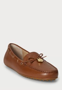 Rjav usnjen mokasin čevelj z detajli vezalk in zlatim kovinskim dodatkom, ima zaobljen nos in teksturirano gumijasto podplato.