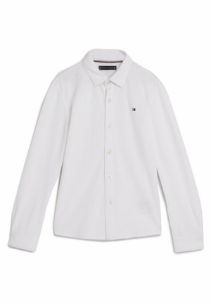 Biała koszula z długim rękawem, z kołnierzykiem i małym logo Tommy Hilfiger po lewej stronie klatki piersiowej.