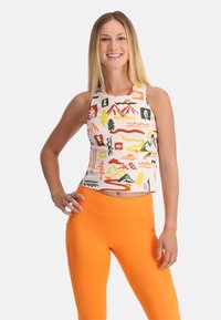 Top corto senza maniche con una stampa colorata di montagne e natura su sfondo bianco, abbinato a leggings arancioni a vita alta.