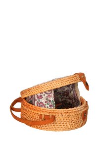 Borsa in rattan intrecciato a forma rotonda, con un tessuto interno colorato e cinghie e dettagli in pelle marrone. Chiusura con un bottone.