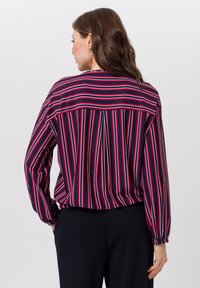 Blouse met lange mouwen met verticale strepen in marineblauw, rood en wit. Heeft een losse pasvorm, geplooide mouwen en een inzettendetail aan de achterkant.