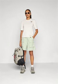 Helehall lühikeste varrukatega särk logoga, mintrohelised vabaajapüksid, hallid matkajalatsid ja helehallide ning musta mustriga seljakott.