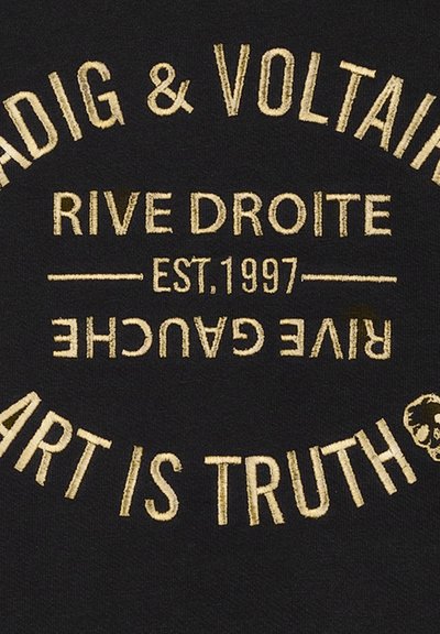 Zwarte stof met gouden geborduurde tekst die "MADE & VOLTAIRE RIVE DROITE EST. 1997 ART IS TRUTH" in een cirkelopmaak leest.
