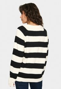 Zwarte en crème gestreepte sweater van zachte stof, met een relaxed fit, brede mouwen en een ribbelrand. Heeft gedurfde horizontale lijnen en een ronde hals.