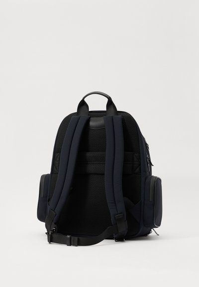 Ναυτικό μπλε σακίδιο πλάτης με μαλακή πλένη πλάτη, ρυθμιζόμενους ιμάντες και πλαϊνές τσέπες. Κατασκευασμένο από ανθεκτικό υλικό με κομψό σχέδιο.