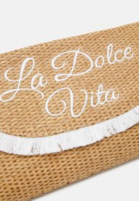 Splotkowa torebka kopertowa z wikliny w odcieniu beżowym, zdobiona białym haftem "La Dolce Vita" oraz frędzlami wzdłuż krawędzi.