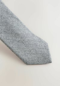 Hallhargiga mustriga lips halli ja valgega. Tekstuuriga kangas, millel on terav ots ja kallutatud lõige, mis näitab kudumist.