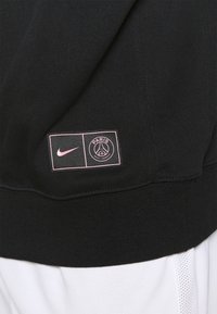 Felpa nera con logo rosa Nike e emblema del Paris Saint-Germain su una toppa rettangolare. Tessuto morbido e texture.