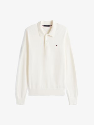 Polo a maniche lunghe di colore crema, realizzato in tessuto morbido. Presenta un colletto, un'apertura con tre bottoni e un piccolo logo sul petto.