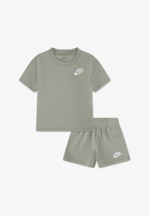 Grau-weißes Nike-Kinder-T-Shirt mit kurzen Ärmeln und ein Set aus Shorts mit elastischem Bund, jeweils mit weißem Nike-Logo auf der Brust und am linken Bein.