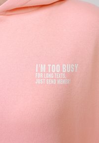 Sweat à capuche rose avec texte blanc sur la poitrine indiquant : "JE SUIS TROP OCCUPÉ POUR LES LONGS MESSAGES, ENVOIE JUSTE DES MEMES !"