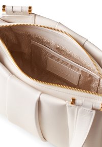 Cream leather handbag with a zippered opening, gold hardware, and a textured interior featuring a label. Includes a pocket inside.