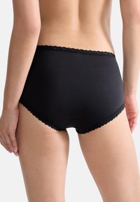 Schwarze Baumwollunterwäsche mit hohem Bund, verziert mit einer gewellten Spitzenkante am Bund und an den Beinausschnitten. Glatte Textur, schlichtes Design.