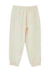 Pantaloni color crema chiaro, con vita elastica, due tasche posteriori e polsini elastici alle caviglie. Texture liscia, design affusolato.