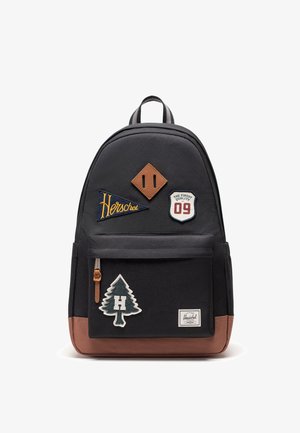 Sac à dos noir avec accents marron, poche avant, écussons dont arbre avec H, logo Herschel, badge 09 et petit détail losange en cuir.