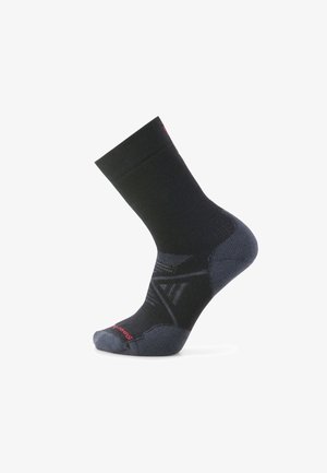 Svart strumpa med ribbad textur, mönstrad design i mörkare nyanser, förstärkt häl och röd branding nära tåområdet.