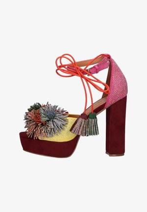 Sandalo con plateau e tacco alto bordeaux, tessuto glitter giallo e rosa, pon pon multicolore e cinturino alla caviglia arancione con nappine.