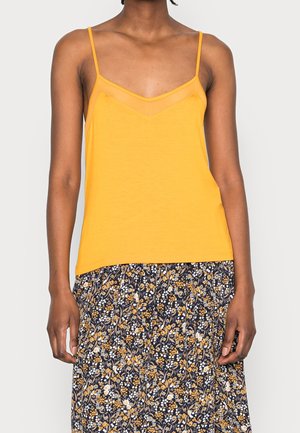 Geel mouwloos topje met een V-hals en doorschijnende accenten bij de halslijn, gecombineerd met een rok met een bloemmotief in donkerblauwe en gele tinten.