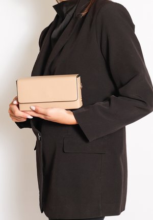 Clutch rettangolare beige con bordo nero, texture liscia e hardware dorato. Tenuto in mano, presenta una chiusura a pattina.