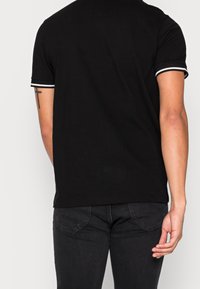 Schwarzes T-Shirt mit kurzen Ärmeln und weißem Kragenrand, aus Baumwolle, taillierte Passform, glatte Textur und ohne sichtbare Muster oder Grafiken.