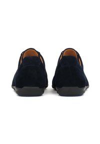 Chaussures en daim bleu marine à enfiler avec un bout arrondi, intérieur marron clair, semelle en caoutchouc noire, présentant un design minimaliste et des détails élastiques sur les côtés.