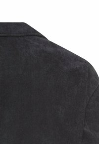 Czarna kurtka dżinsowa z teksturowanym materiałem, charakteryzująca się usztywnionym kołnierzem oraz subtelnymi detalami przeszycia. Użyteczny design z klasycznym krojem.