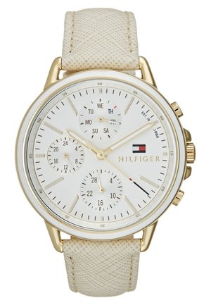 Montre-bracelet dorée avec cadran blanc, bracelet en cuir texturé beige, jour, date, sous-cadrans 24 heures et logo Tommy Hilfiger sur le cadran.