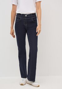 Jeans en denim bleu foncé avec une coupe droite, des coutures jaunes contrastantes, des poches avant et une fermeture à bouton à la taille.
