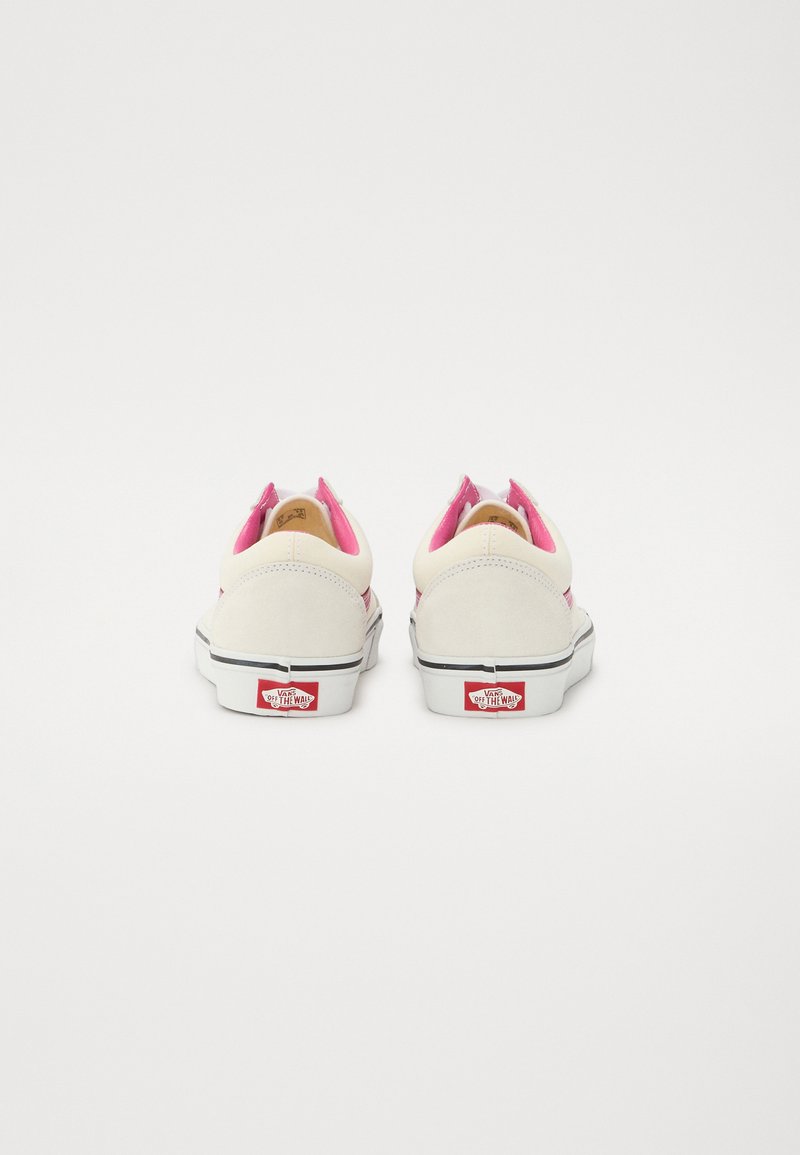 Zapatillas blancas con acentos rosas; materiales de ante y lona; diseño de perfil bajo con suela negra contrastante; logo clásico en el talón.