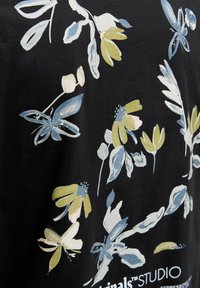 Schwarzer Stoff mit floralem Muster aus blauen, gelben und weißen Blüten und Blättern; enthält den Text: "originals™ STUDIO."