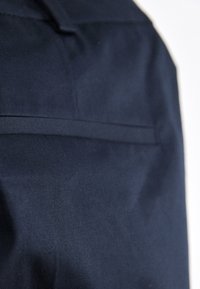 Námořnická modrá látka s hladkým povrchem, s horizontálním švem ve středu. Jednoduchý design bez viditelného kovového příslušenství nebo vzorů.