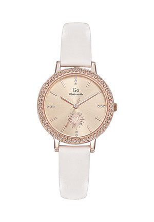 Montre ronde en or rose avec lunette ornée de cristaux, cadran beige, design soleil en forme de cœur, index horaires minimalistes, et bracelet en cuir blanc.